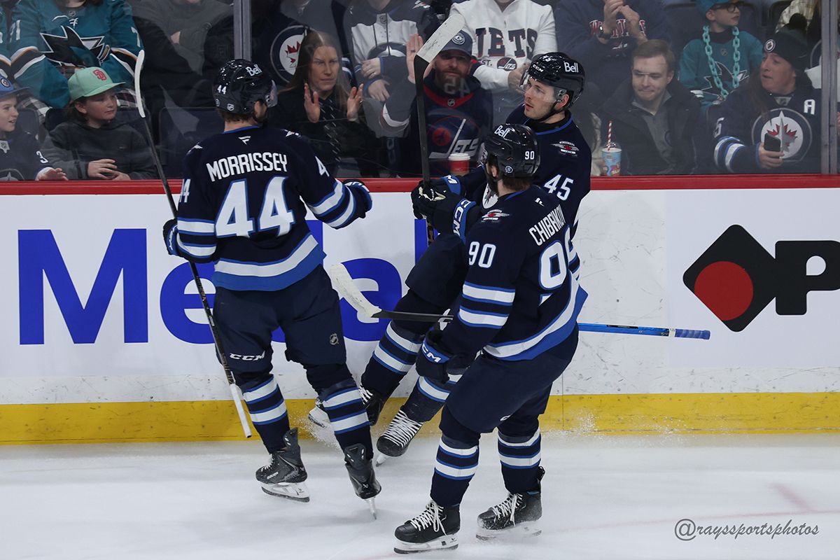 3 hockey players in Winnipeg Jets uniforms come together in celebration